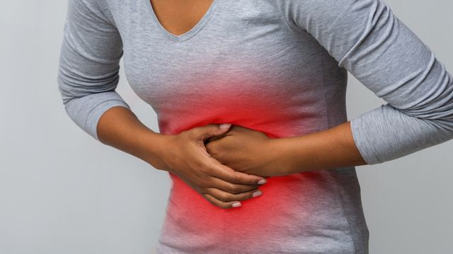 Mujer con gesto de dolor tocándose el abdomen por posible desgarro muscular abdominal